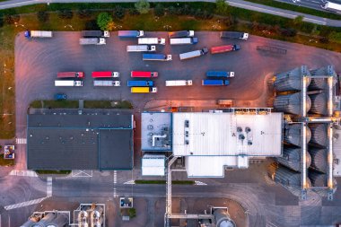Birçok kamyon fabrikadaki deponun yakınında yükleme için bekliyor. Endüstriyel alanın havadan görüntüsü, fabrika.