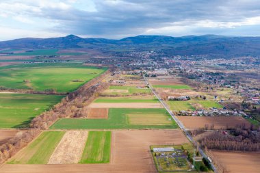 Dağın eteğindeki küçük bir Polonya kasabası. Küçük evler ve bir kilise. Ignor tarlalarında kuş bakışı manzara