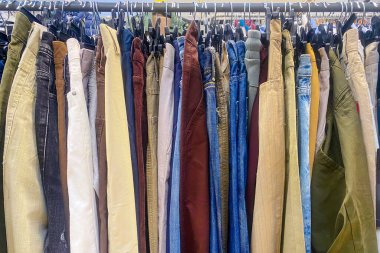 Askıda bir sürü renkli pantolon asılı.