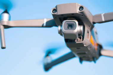 Mavi gökyüzüne karşı uçan bir kuadkopter, gökyüzünde bir dron.