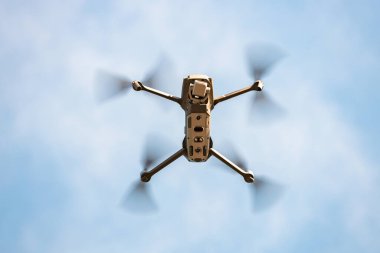 Mavi gökyüzüne karşı uçan bir kuadkopter, gökyüzünde bir dron.