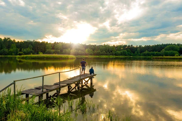 Chłopcy Starym Drewnianym Moście Nad Jeziorem Wędkowanie Zachodzie Słońca Letni — Zdjęcie stockowe