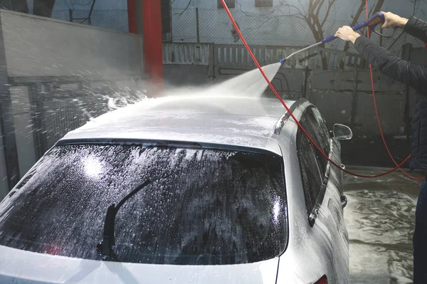 Hand washing with high pressure water, spraying water on the car. Self-service car wash