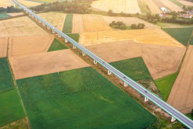 Top view of bridge road over green fields