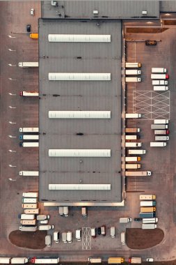Aerial view of a warehouse with goods. Logistics center in the industrial zone of the city, many trucks are waiting for loading in the logistics warehouse