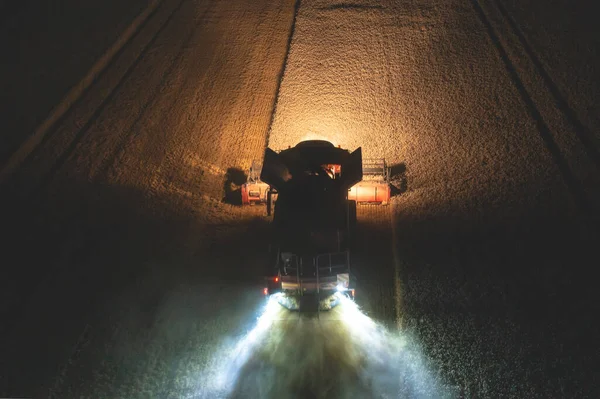 Aerial view of harvester harvesting wheat at night