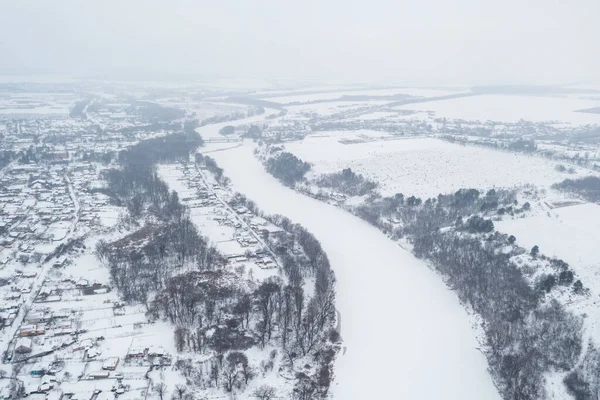 Aerial view of a frozen river. The river is frozen and covered with snow, severe frosts