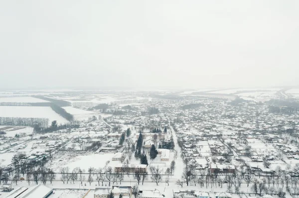 View from a height of a small village in winter. Snowy village, snow-covered houses and roads. February weather in Ukraine