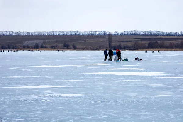 Many people on ice, winter fishing, frozen river in winter, ice fishing