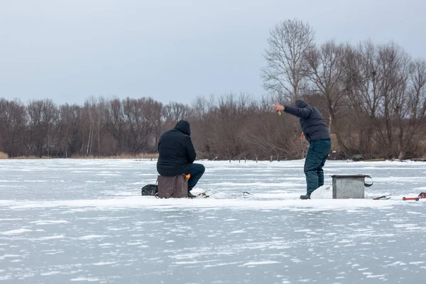 Ice fishing on ice, a fisherman sits on a fishing chest and catches fish on a frozen lake