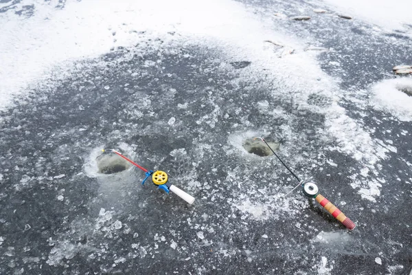 Fishing rods lie on the ice near the ice hole, winter fishing on a frozen lake