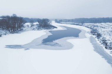Karla kaplı donmuş bir nehrin yüksekliğinden bak. Soğuk kış. Nehirde güzel buz desenleri var.