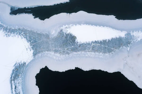 Ice melts on the river. Water washes ice, beautiful patterns of ice and water, aerial view of a frozen river
