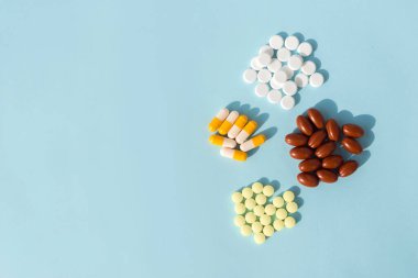 Farklı ilaç hapları, tabletler ve açık mavi arka planda kapsüller. Boşluğu kopyala.