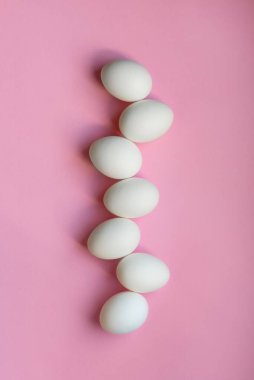 Açık pembe arka planda beyaz yumurtalar. 