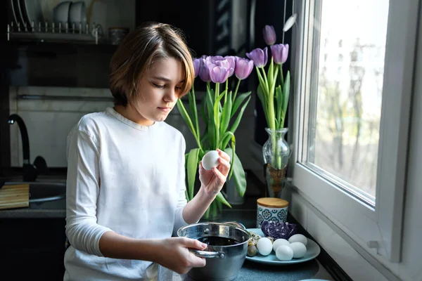 Genç çocuk Paskalya tatili için yumurta boyuyor. Geleneksel Paskalya hazırlığı.