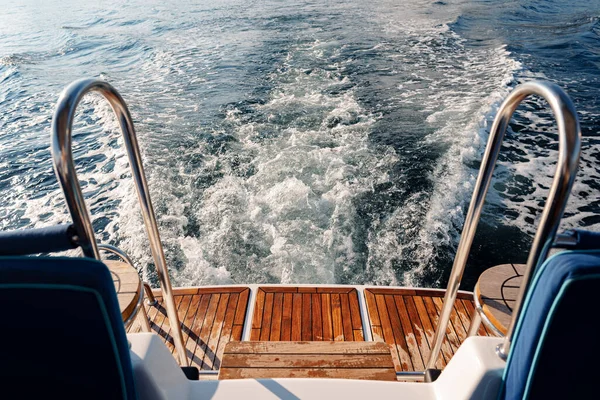 Motorlu yat denizde yüzüyor, kıç tarafından görünüyor.