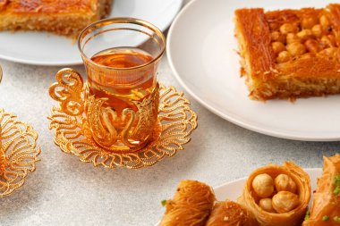 Beyaz dokulu arka planda çeşitli Türk tatlıları ve bir fincan çay