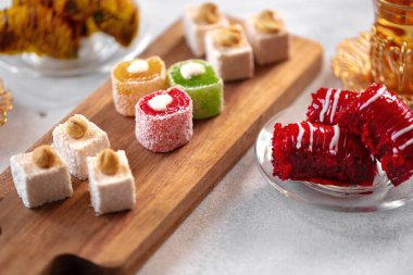 Beyaz dokulu arka planda çeşitli Türk tatlıları ve bir fincan çay