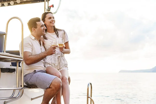 Junges Liebespaar sitzt auf dem Jachtdeck und trinkt Wein — Stockfoto