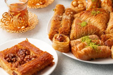 Beyaz dokulu arka planda çeşitli Türk tatlıları ve bir fincan çay