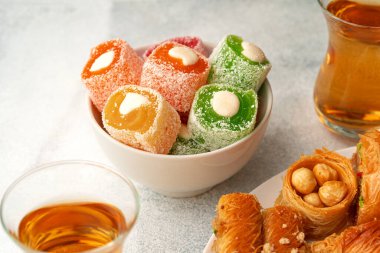 Beyaz dokulu arka planda çeşitli Türk tatlıları ve bir fincan çay