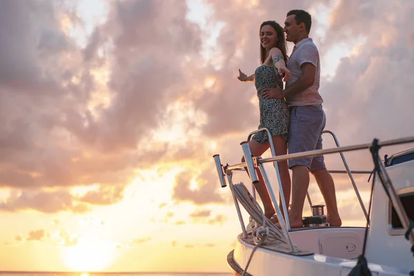 Beau couple regardant le coucher du soleil depuis le yacht — Photo