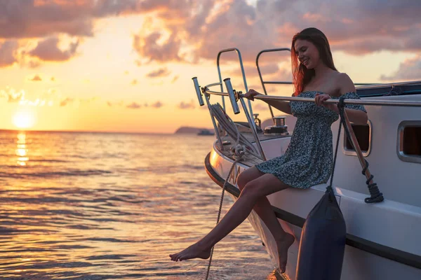 ヨットのデッキに座って夕日を楽しむ若い魅力的な女性 — ストック写真