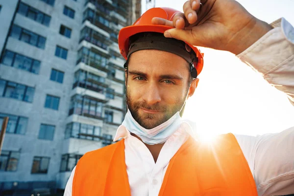 Retrato de homem construtor em workwear e hardhat vestindo máscara médica, close up — Fotografia de Stock