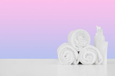 Havlu yığını, beyaz masada şampuanlı şişeler.