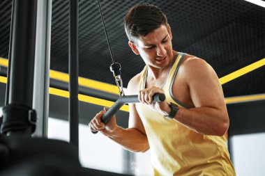 Genç vücut geliştirici spor salonunda pazılar için ağır ağırlık egzersizi yapıyor.