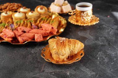 Siyah arka planda bir fincan kahve ile Türk tatlı baklavası