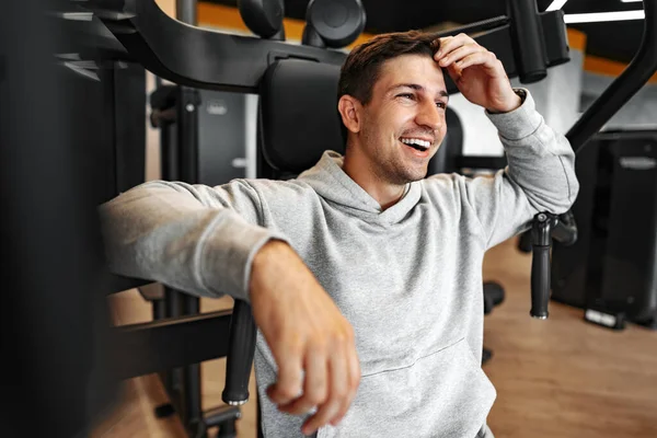 Hombre culturista en forma joven haciendo entrenamiento de brazos en el gimnasio en la máquina —  Fotos de Stock