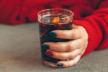 Elleri sıcak süveter giymiş kadınlar bir bardak sıcak şarap tutarlar.