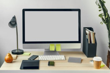Ofis masasında malzemelerle birlikte beyaz ekranlı bilgisayar monitörü