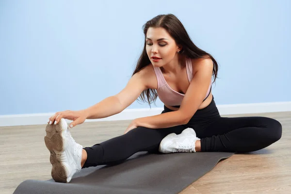 Jonge mooie sportieve vrouw doen stretching inspanningen op een vloer — Stockfoto