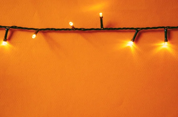 Fundo laranja com luzes iluminadas de guirlanda — Fotografia de Stock