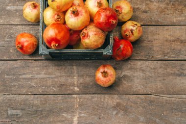 Tahta arka plandaki eski bir kutuda taze nar.