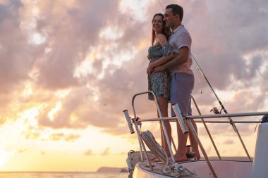 Beautiful couple looking at sunset from the yacht clipart