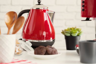 Mutfak rafında kırmızı çatal bıçak ve bulaşık takımı var.