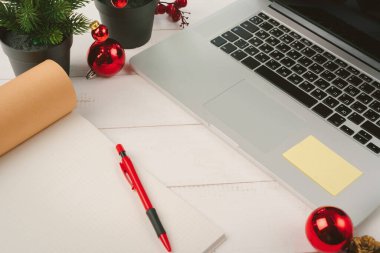 Masadaki dizüstü bilgisayarı ve defteri noel dekoruyla aç