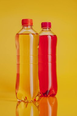 Parlak sarı arka planda içki dolu plastik şişe