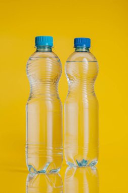 Parlak sarı arka planda içki dolu plastik şişe