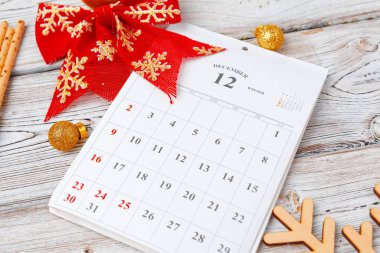 Ahşap arkaplanda kırmızı kurdeleli Aralık takvim sayfası