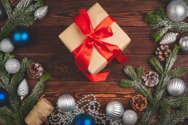 Ahşap arka planda kurdeleyle süslenmiş şık bir Noel hediyesi.