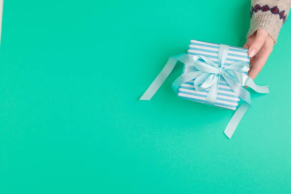 Woman hands holding gift box on green background — Stock Photo, Image