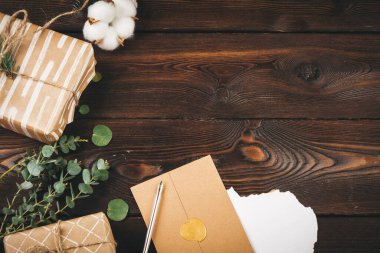 Noel eşyalarıyla süslenmiş, eski ahşap arka planda tüy olan boş bir mektup.