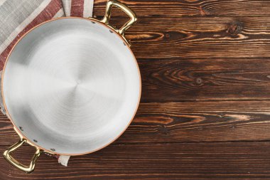 Tahta masa örtüsü olan bakır tencere.