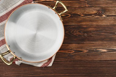 Tahta masa örtüsü olan bakır tencere.