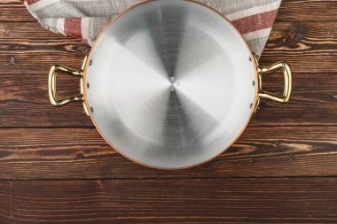 Tahta masa örtüsü olan bakır tencere.